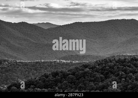 The setting sun creates a bisecting line of light on rolling mountains on the Blue Ridge Parkway near Asheville, NC, USA. Stock Photo