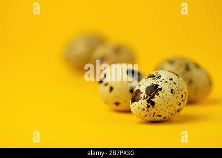 Quail eggs close-up on a yellow background.Easter holiday symbol.Easter card,copy space.Macro photo. Stock Photo