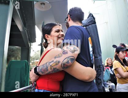 Young couple hugging, her smiling face and him with tattoos but both happy at being together Stock Photo