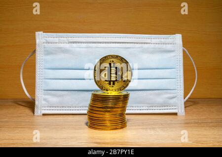 Gold Bitcoin coins with a medical mask. A business finance concept Stock Photo