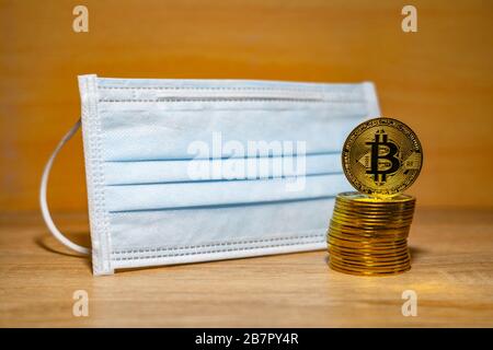 Gold Bitcoin coins with a medical mask. A business finance concept Stock Photo