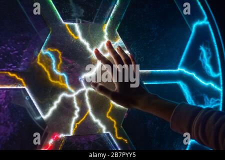 Electricity, science and physics concept - woman touching plasma panel display Stock Photo