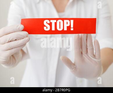 Coronavirus quarantine, red warning sign with text Stop, doctor show stop hands gesture for stop corona virus outbreak. Doctor hands in white coat Stock Photo