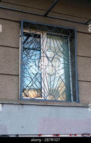 Window with gray metal bars. A plastic window in the building on the ground floor with a curly flat lattice. Stock Photo
