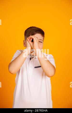 The boy looks like through binoculars. Hands folded into a straw. Boy is watching looking through hands Stock Photo