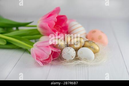 golden colored eggs for Easter holiday in April with tulips flowers Stock Photo