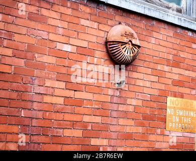 Vintage fire alarm warning bell outside brick industrial building Stock Photo