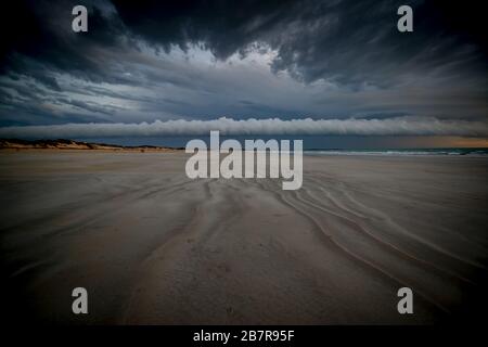 Cable Beach surrounded by the sea under a cloudy sky during the sunset in Australia Stock Photo