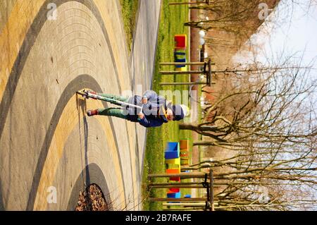 POZNAN, POLAND - Mar 08, 2020: Young boy riding a scooter on a footpath in the Rataje park. Stock Photo