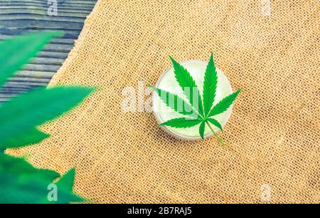 CBD Cannabidiol hemp balm lotion on hemp cloth and leaf Stock Photo