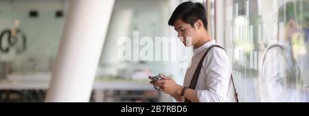 Side view of young male photographer checking his picture on digital camera while standing in glass wall co-working space Stock Photo
