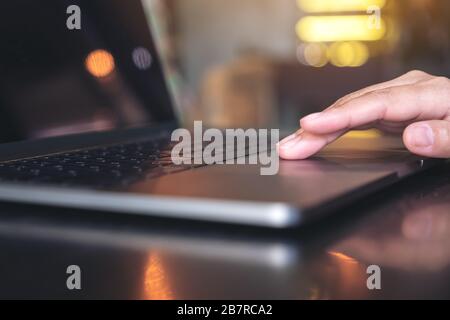 Closeup image of hand using and touching on laptop touchpad on table Stock Photo