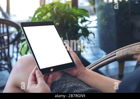 Mockup image of a woman holding black tablet pc with blank white screen while sitting in the outdoors Stock Photo