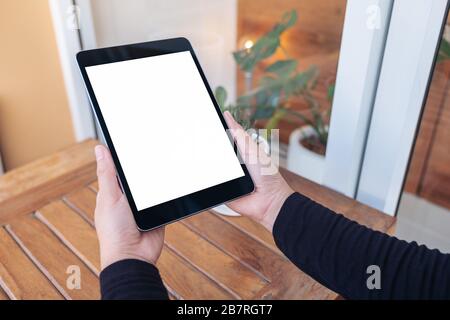 Mockup image of hands holding and looking at black tablet pc with blank white screen Stock Photo