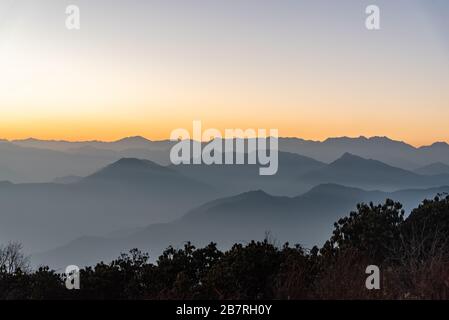 Stacked mountain ridges seen during golden hour of sunset from Poonhill Ghorepani Nepal Stock Photo