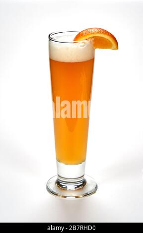 Highball tall glass of unfiltered white beer with a slice of orange over white background. Beer is one of the oldest, most popular and widely consumed Stock Photo