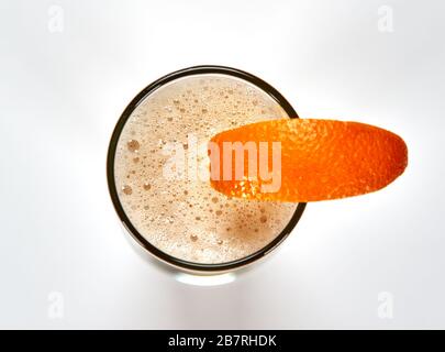 Highball tall glass of unfiltered white beer with a slice of orange over white background. Beer is one of the oldest, most popular and widely consumed Stock Photo