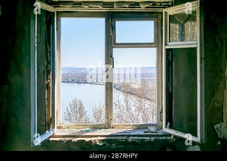 view of the river and the village from an old open window of an abandoned house on the top of a mountain Stock Photo