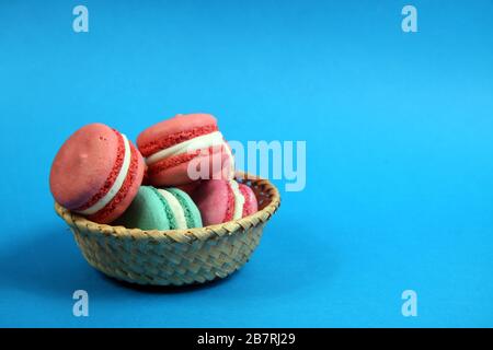 macaroons of different colours in a basket on blue background flat lay. Image contains copy space Stock Photo