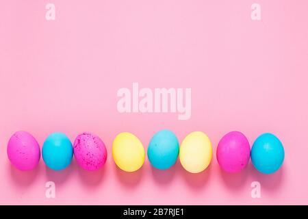 Happy easter concept. Colored eggs lie in a row on a pink background. Copy space flat layout. Banner with place for text advertising. Stock Photo