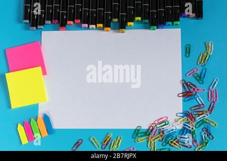 Multi-colored markers, paper clips, stickers and paper on a blue background. Drawing and creativity. Stock Photo
