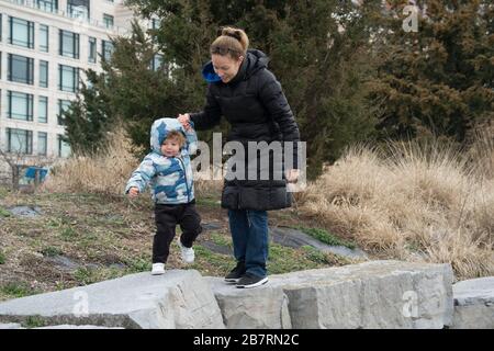 A mother helped her daughter clamber over some large stones in Hudson River Park. The park runs along the Hudson River between Chambers Street and mid Stock Photo