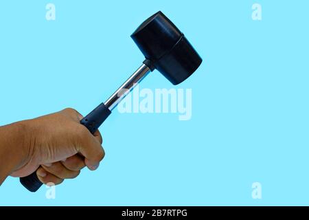 Man's hand holding hammer on blue background. Copy space Stock Photo