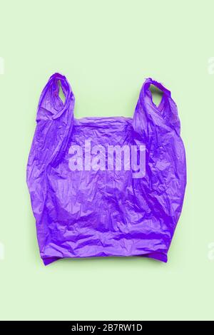 Purple plastic bag on green background. Environment pollution concept. Top view Stock Photo