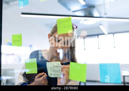 Caucasian woman writing on a sticky note Stock Photo