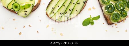 top view of fresh cucumber toasts with seeds, mint leaves on white background, panoramic shot Stock Photo