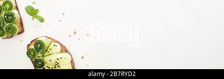 top view of fresh cucumber toasts with seeds, mint on white background, panoramic shot Stock Photo