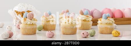Delicious cupcakes with colorful painted chicken and quail eggs near easter cake on grey background, panoramic shot Stock Photo