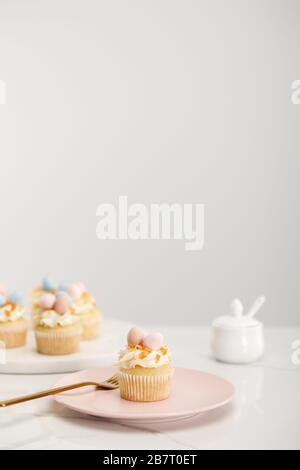 Selective focus of cupcakes on plate and round board near sugar bowl on grey background Stock Photo