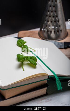 Basil leaveson a desk with a notebook for recipes and notes a composition with negative space a background for advertsing Stock Photo