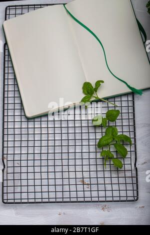 Basil leaveson a desk with a notebook for recipes and notes a composition with negative space a background for advertsing Stock Photo