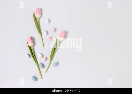 Border frame made of easter eggs and flowers on a blue pastel background. Holiday concept with copy space. Stock Photo