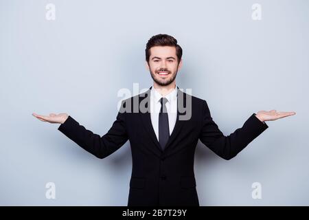 Portrait of handsome young smiling man in suit asking to make a choice between two products on his palms Stock Photo
