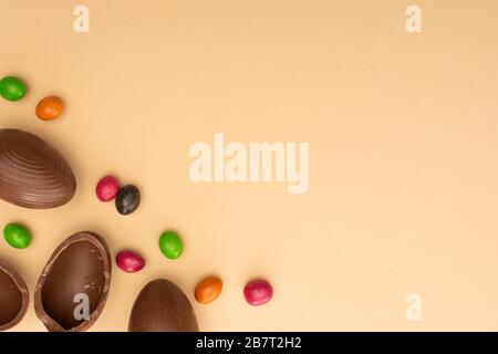 Top view of chocolate eggs and sweets on beige background Stock Photo