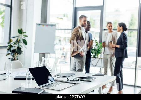 selective focus of businesspeople holding disposable cups of coffee and workspace on foreground Stock Photo
