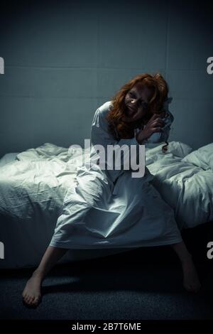 crazy female demon in nightgown sitting on bed Stock Photo - Alamy