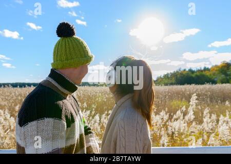 Happy young multi ethnic couple looking at scenic view of autumn bulrush field together Stock Photo