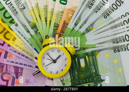 Yellow alarm clock and Euro banknotes of different denominations Stock Photo