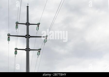 Pillar and power lines against a cloudy sky Stock Photo
