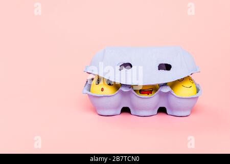 Easter eggs with funny facial expressions in egg tray on pink Stock Photo