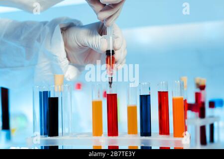 cropped view of scientist in latex gloves holding syringe near test tubes Stock Photo