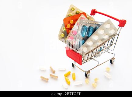Miniature shopping cart filled with pills, tablets and capsules: pharmacy shopping, medicine and drug abuse concept. Coronavirus concept. Stock Photo