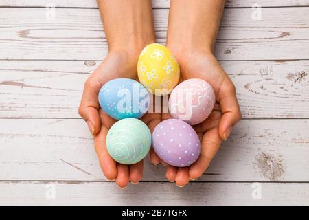 easter concept. closeup beautiful woman hands holding hand-painted easter eggs in tender pastel colors over wooden table Stock Photo