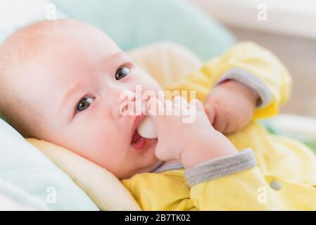 Introduction of complementary foods. The baby will eat children's mashed. Infant with a spoon in a high chair for feeding. Stock Photo