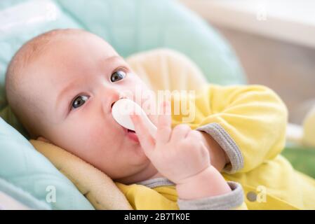 Introduction of complementary foods. The baby will eat children's mashed. Infant with a spoon in a high chair for feeding. Stock Photo