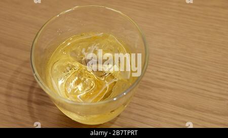 https://l450v.alamy.com/450v/2b7tprt/a-glass-of-whisky-with-ice-cubes-on-top-of-a-simple-wooden-table-2b7tprt.jpg